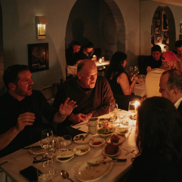 Dining scene with people seated at a table in a dimly lit restaurant, featuring the Egress Sconce in the background.